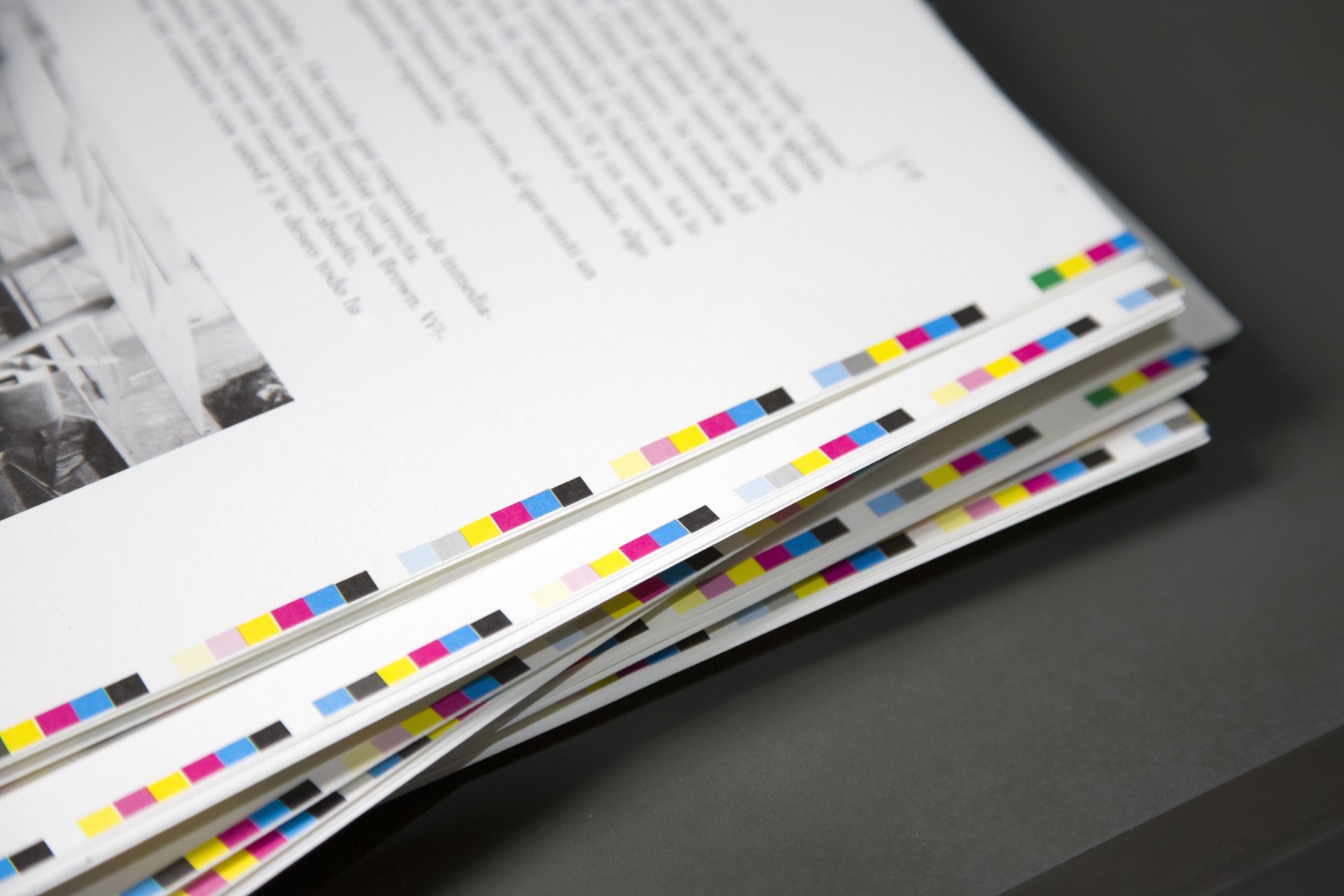 White sheets with with the text and paint around the edges are stacked in a printing house.