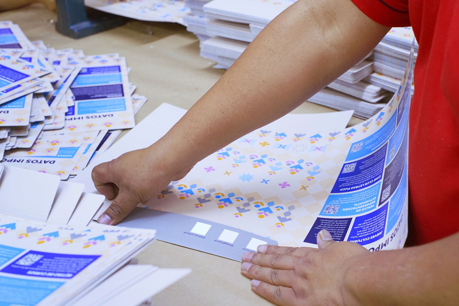 Close-up of man's hands folding printed brochures at a workplace
